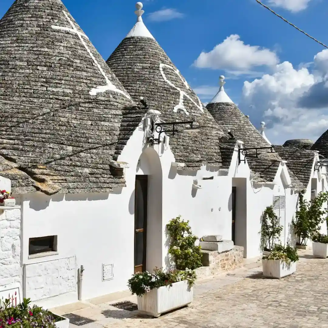 Traditional stone Trulli overlooking the lush Carlo Sani vineyards in Puglia, representing the authentic winemaking heritage of Southern Italy